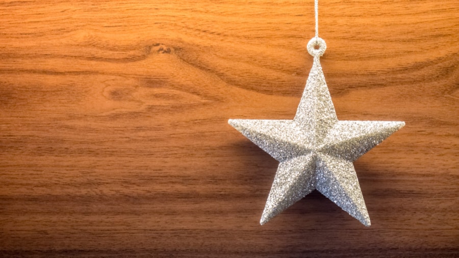 Silver glittering star ornament on wooden background leaving copyspace on the left